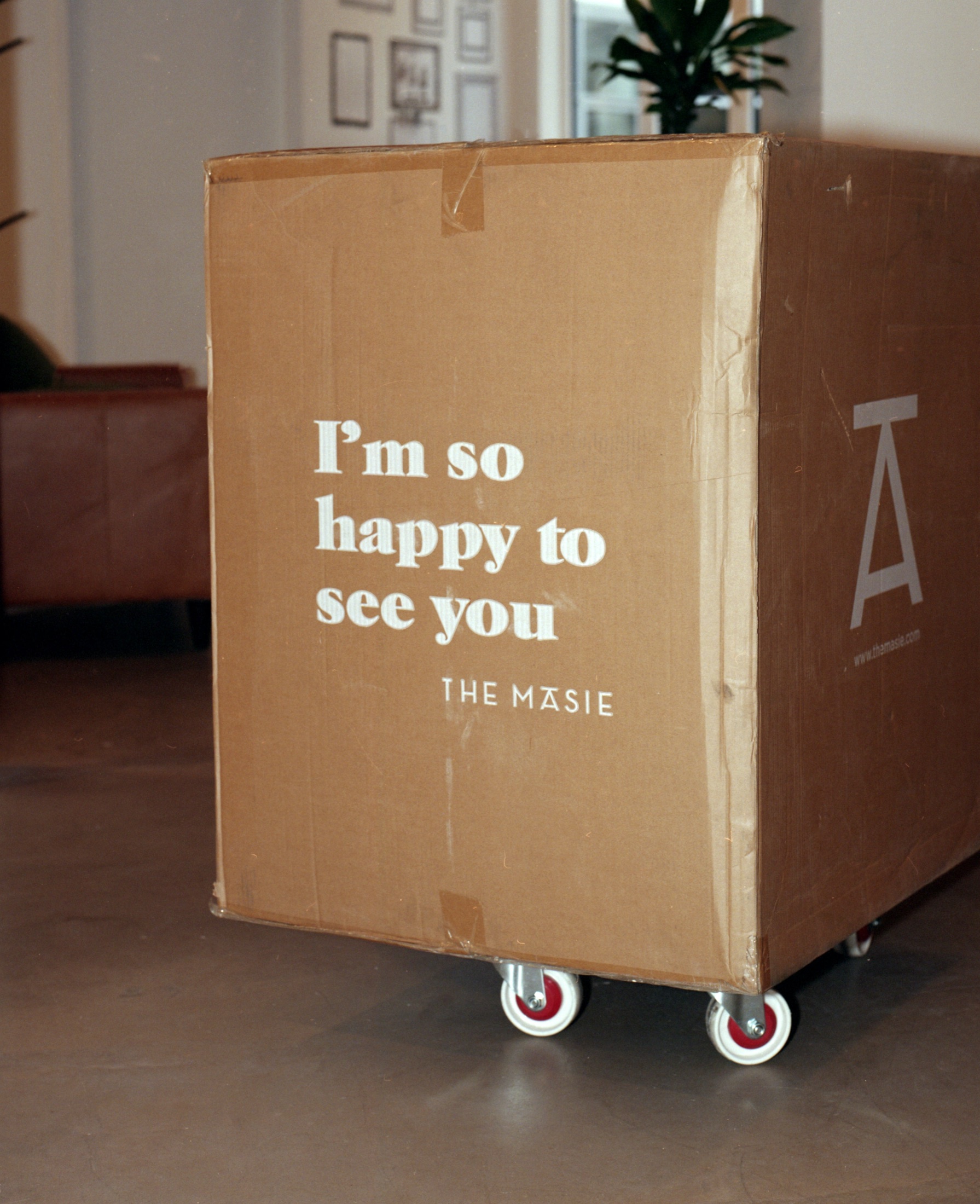 Carton de déménagement sur roulettes portant l'inscription I'm so happy to see you