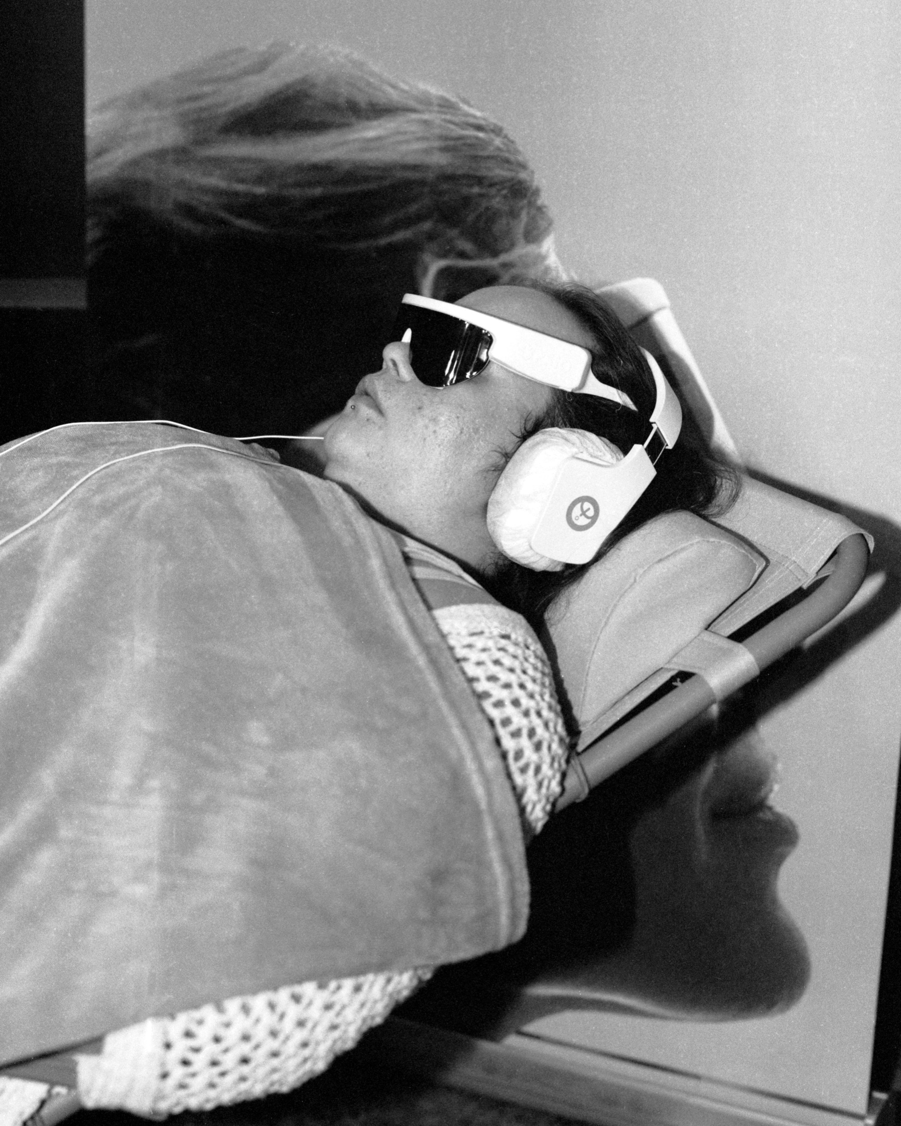 Personne allongée portant un casque de réalité virtuelle, noir et blanc