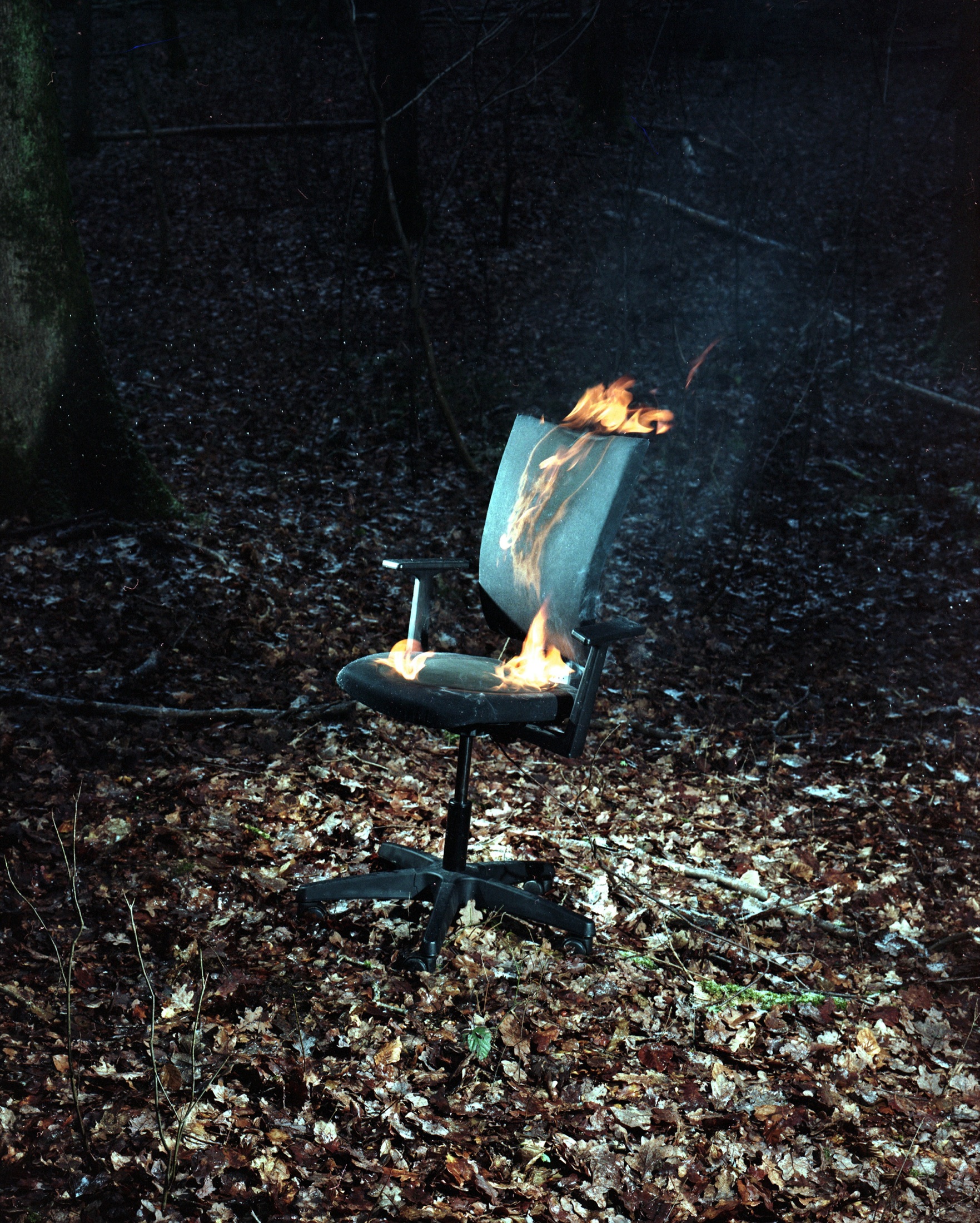 Chaise de bureau en feu dans un sous-bois, la nuit